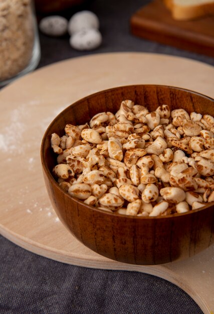 Side view of bowl full of corns on cutting board on maroon background