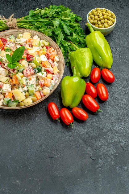 Side view of bowl of vegetable salad with vegetables on side with free place for your text on bottom on dark grey background