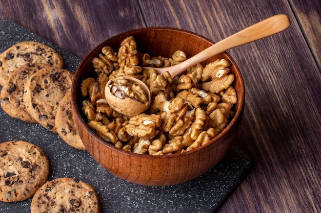 side view in a bowl with peeled walnuts with oatmeal chocolate cookies on a board