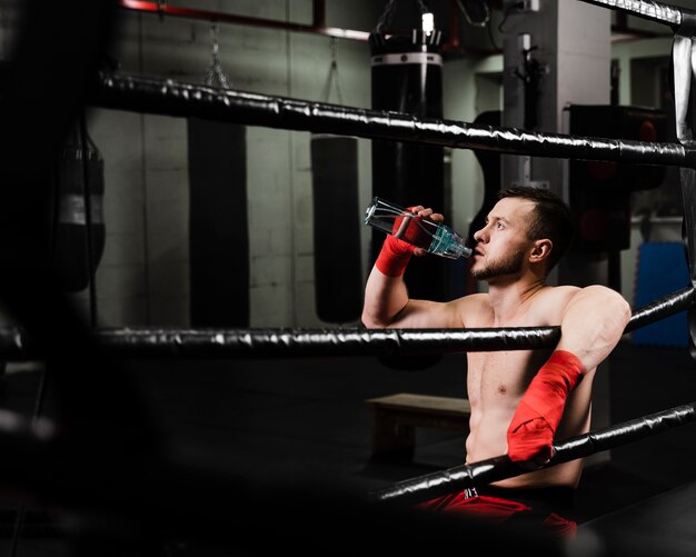 Foto gratuita boxer vista laterale prendendo una pausa dall'allenamento