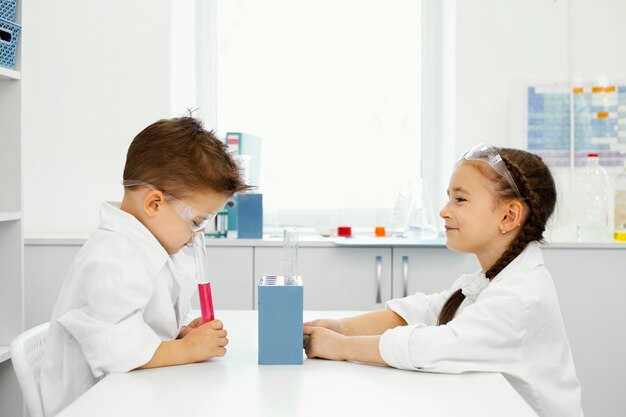 안전 안경 실험실에서 소년과 소녀 과학자의 측면보기
