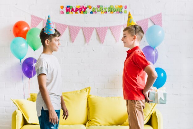 Side view of boy hiding gift from his friend at home