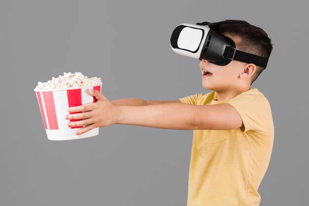 Side view of boy holding popcorn and wearing virtual reality headset