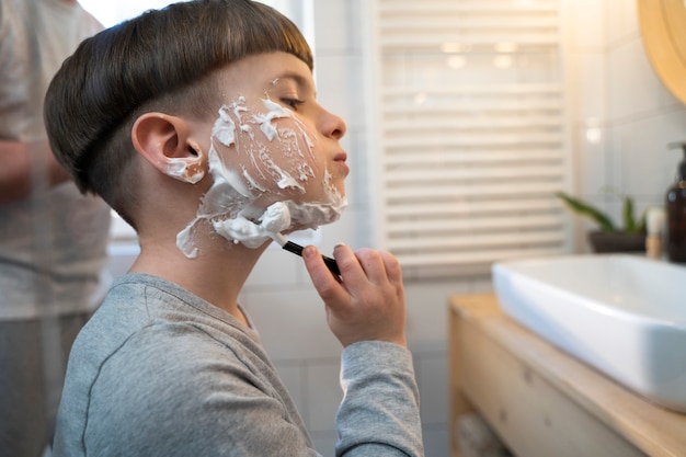 Free photo side view boy learning how to shave