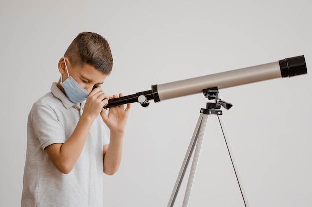 Мальчик, вид сбоку учится пользоваться телескопом