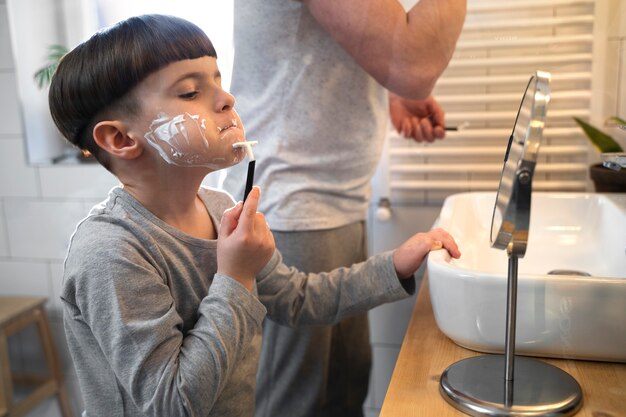 Side view boy learning to shave with mirror