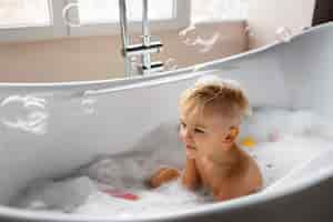 Free photo side view boy playing in bathtub