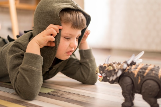 Side view boy playing with dinosaur