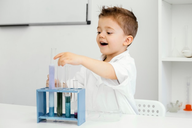Side view of boy scientist in the laboratory doing experiments with test tubes