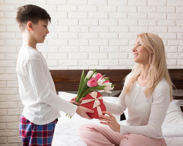 Free photo side view boy surprising his mom