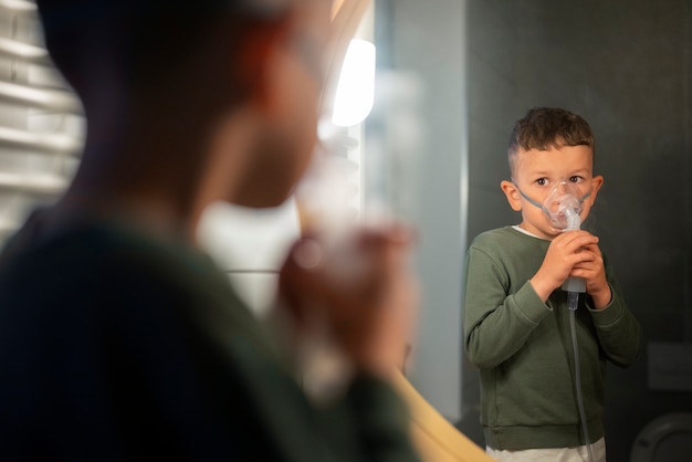 Side view boy using a nebulizer