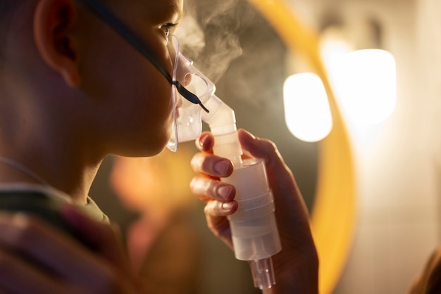 Free photo side view boy using a nebulizer