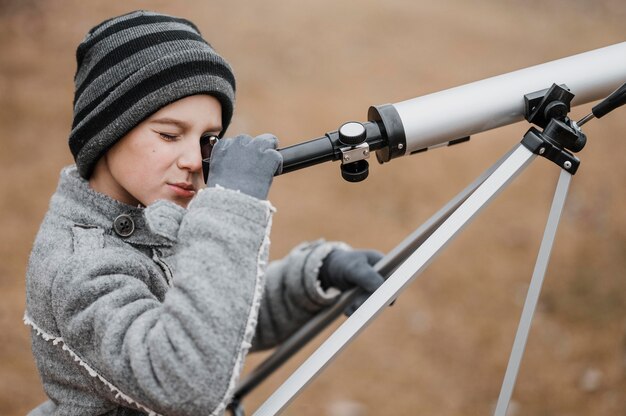 Мальчик вид сбоку с помощью телескопа