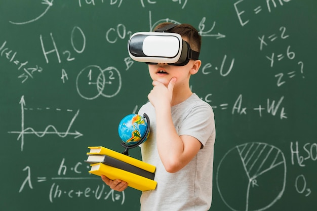 Foto gratuita vista laterale del ragazzo che indossa le cuffie da realtà virtuale e che tengono i libri
