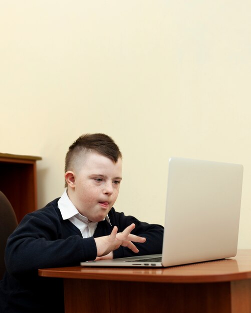 Side view of boy with down syndrome looking at laptop