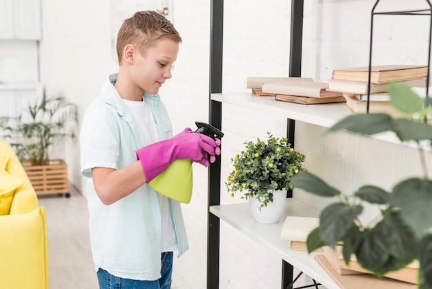 植物に水をまくゴム手袋を持つ少年の側面図