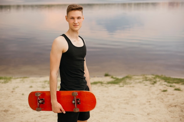 Side view boy with skateboard near the lake