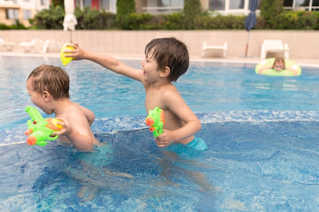 Боковой вид мальчики играют в бассейне