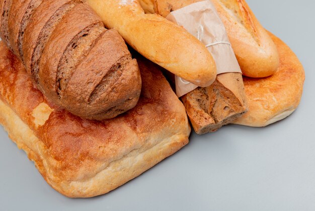 Side view of breads as black homemade crispy and vietnamese baguettes tandir on blue surface