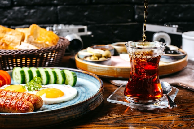 目玉焼きとソーセージの新鮮な野菜チーズとハムの朝食用テーブルの側面図