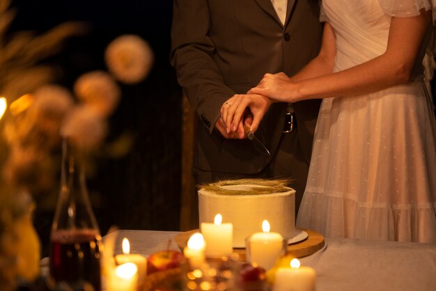 Вид сбоку жених и невеста режут торт