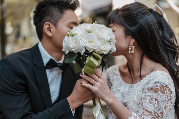 Side view of bride and groom hiding faces behind bouquet of flowers