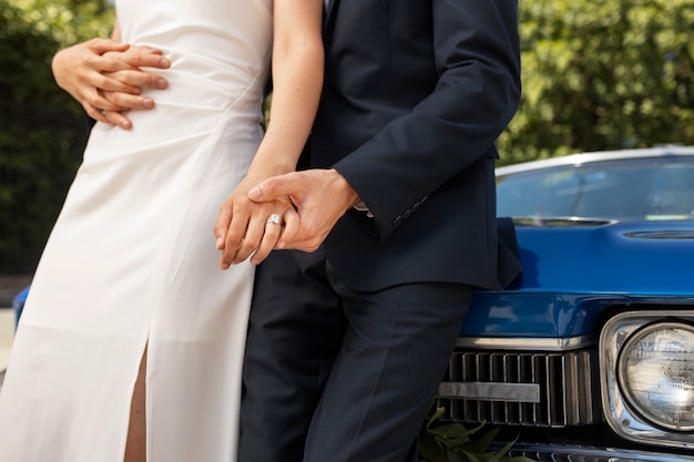 Free photo side view bride and groom near car