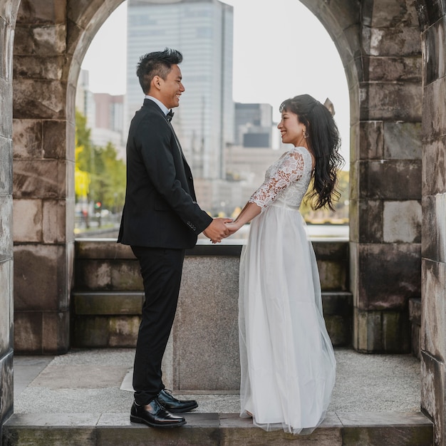 Side view of bride and groom posing together outdoors