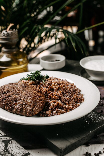 Side view of buckwheat with meat cutlet and herbs on the table