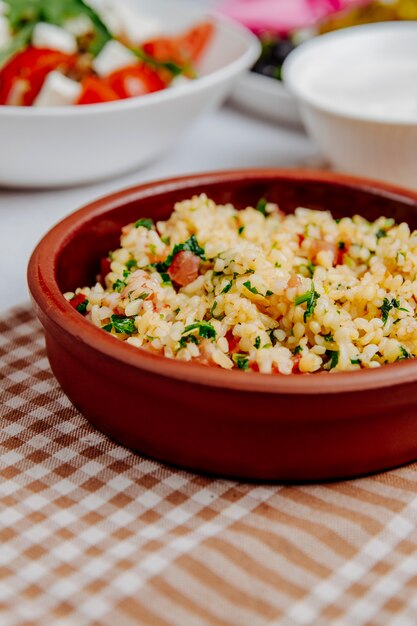 Side view of bulgur with tomatoes in a wooden bowl