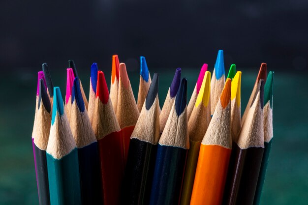 Side view of a bunch of colored pencils on dark