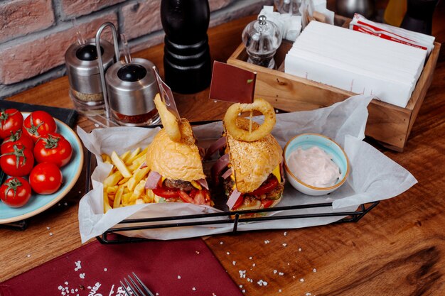 Side view of burger with french fries and sour yogurt on the table