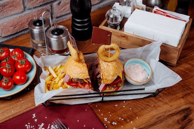 Side view of burger with french fries and sour yogurt on the table