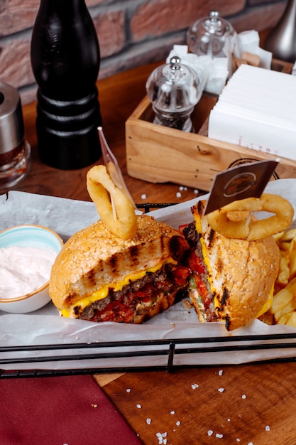 Side view of burger with french fries and sour yogurt on the table