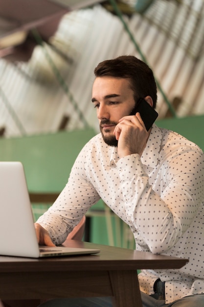 Uomo di affari di vista laterale che parla al telefono