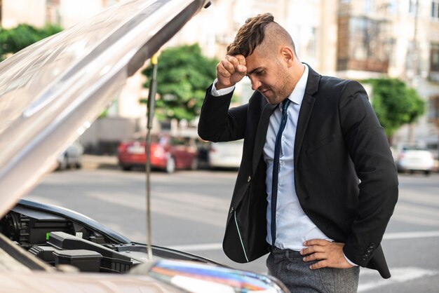 Side view business man trying to fix his car