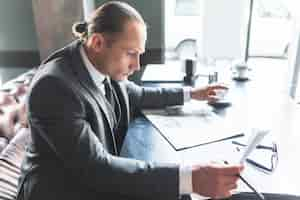 Free photo side view of a businessman checking document in caf�