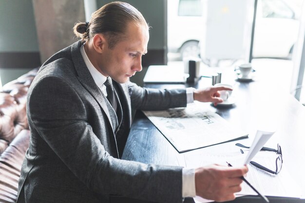 Side view of a businessman checking document in caf�