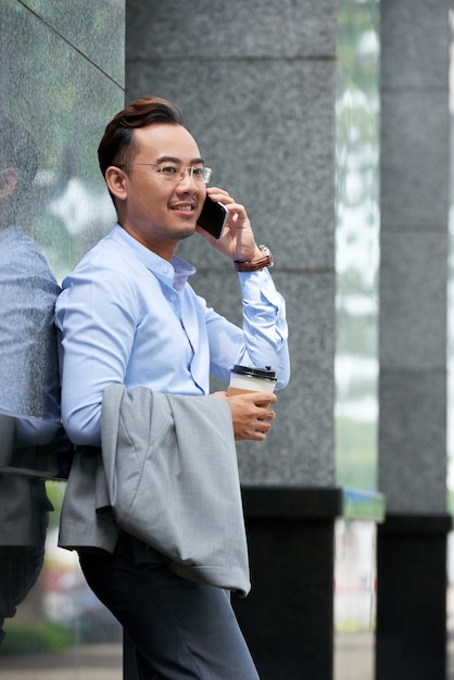 Бизнесмен, разговаривающий по телефону на улице в летний день