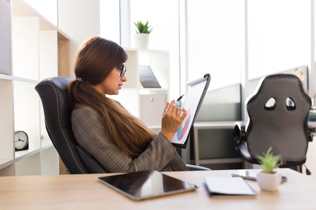 Free photo side view of businesswoman at desk with notepad