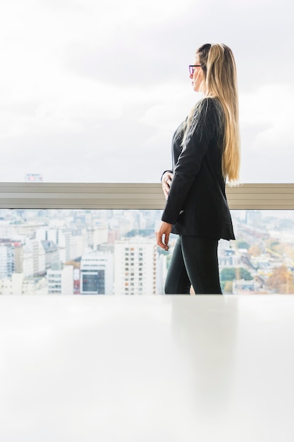 Side view of businesswoman standing near the window glass in the office