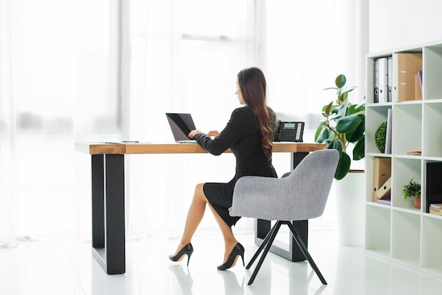 Side view of a businesswoman using laptop in the office