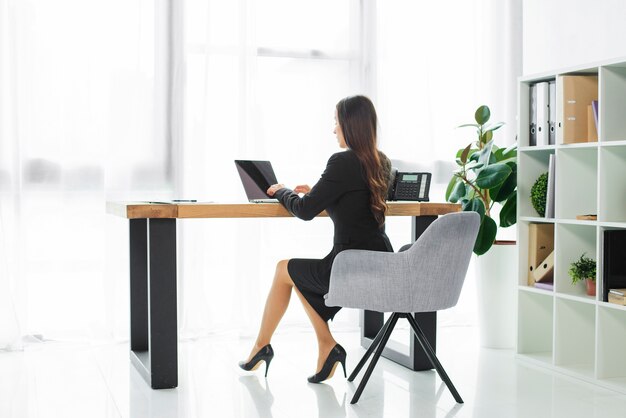 Side view of a businesswoman using laptop in the office