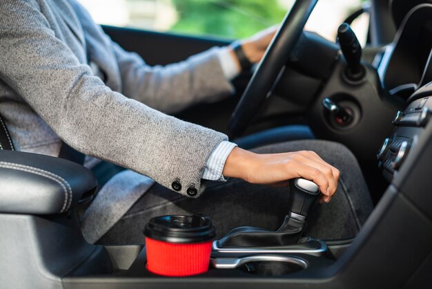 Side view of businesswoman using the stick shift of her car