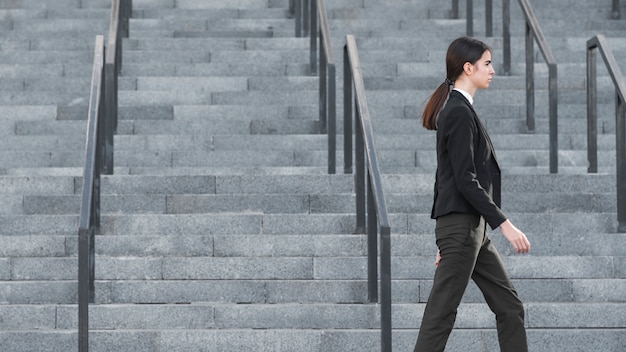 Free photo side view of businesswoman walking past stairs
