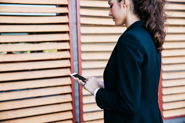 Foto gratuita vista laterale della donna d'affari con smartphone