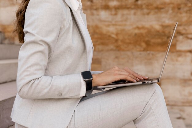Side view of businesswoman with smartwatch working on laptop outdoors