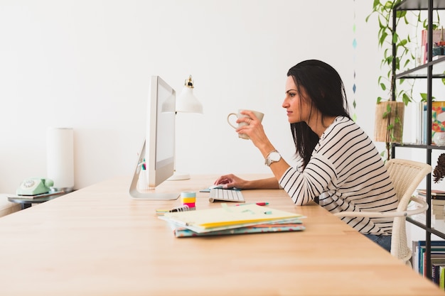 Side view of businesswoman working with a computer and holding a cup