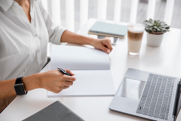 Side view of businesswoman working with notebook and laptop