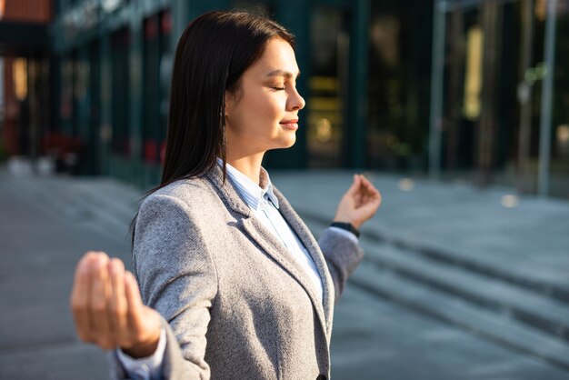 Side view of businesswoman in zen pose in the city